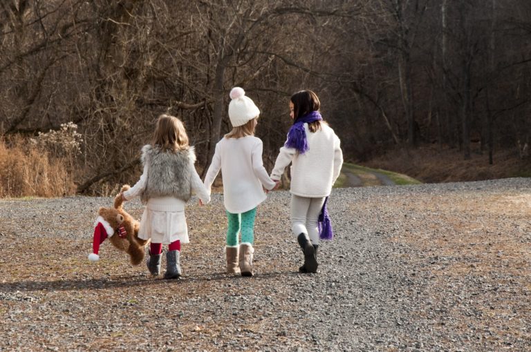 three girls walking together with Christmas bear